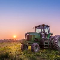 tractor sitting in a field at sunset