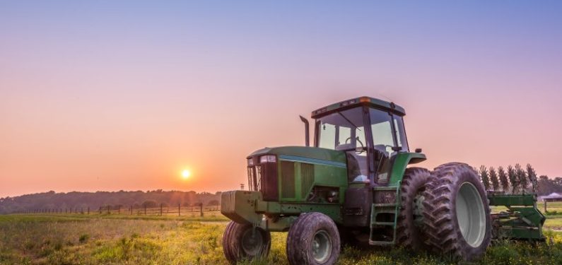 tractor sitting in a field at sunset